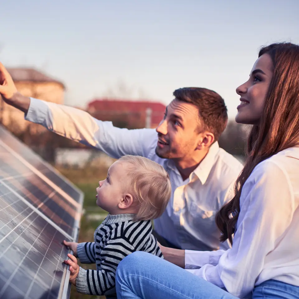 Familie sitzt vorm Solarpanel.