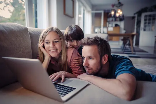 Familie sitzt gemeinsam vorm Laptop.