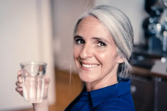 Frau mit Wasserglas in der Hand.