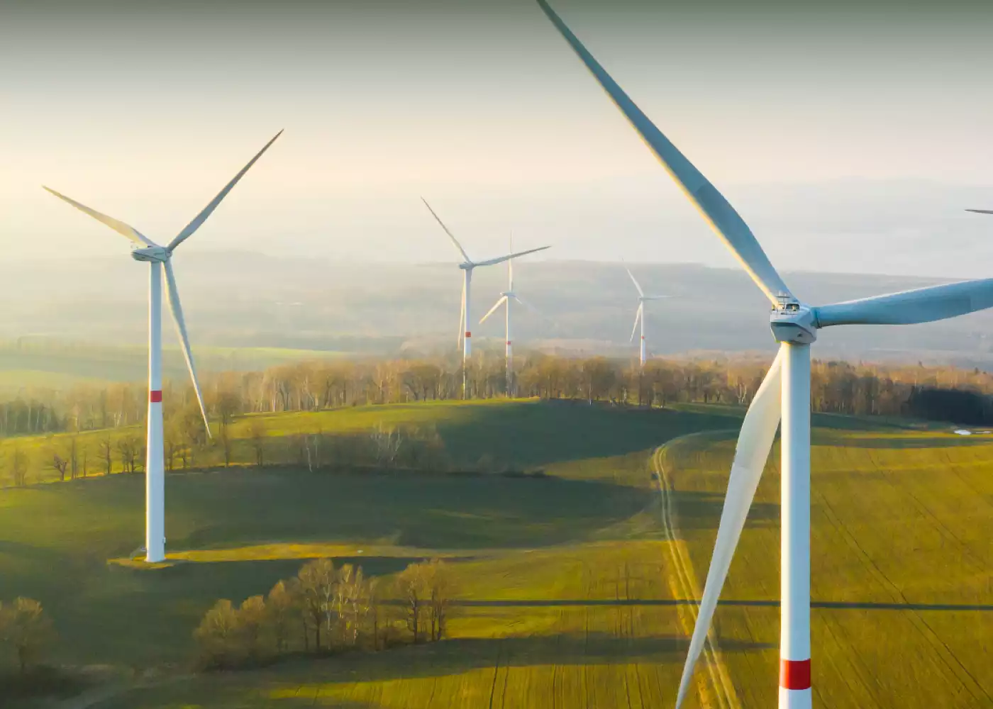 Foto einer leicht hügeligen Landschaft mit Windrädern. Der Himmel ist leicht bewölkt.